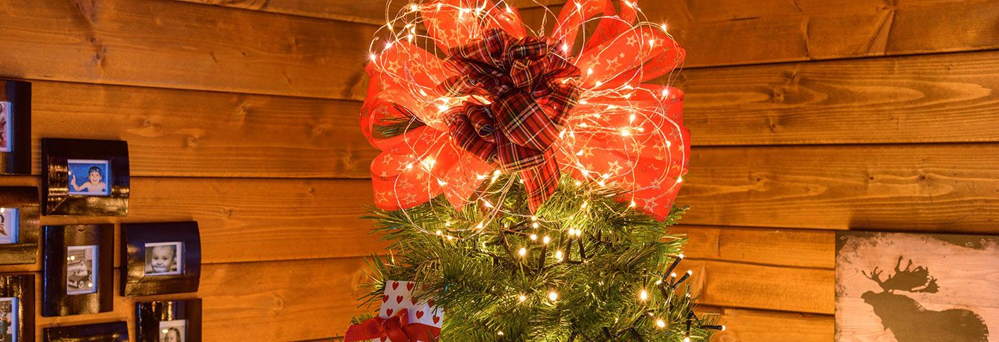 Nœud rouge et micro-LED utilisés comme cimier au sommet d’un sapin de Noël
