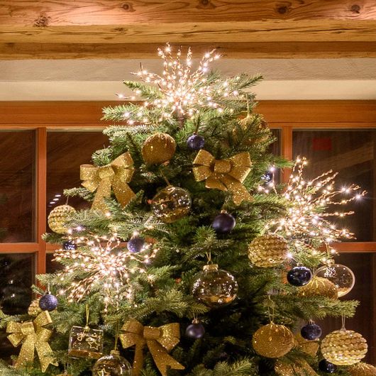TwigBall a luce calda tra fiocchi e palline oro sulla cima dell’albero di Natale