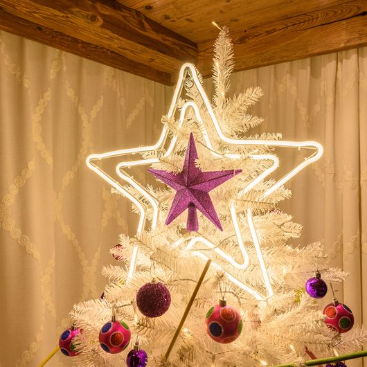 Stella luminosa doppia a luce calda sulla punta di un albero di Natale bianco