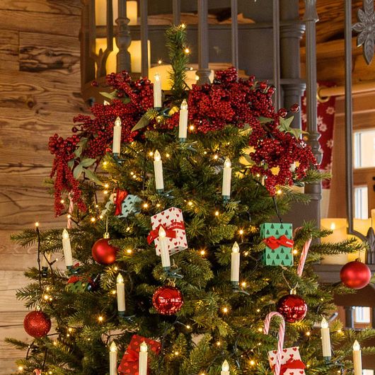 Rami di bacche rosse usati come puntale di un albero di Natale con candele LED