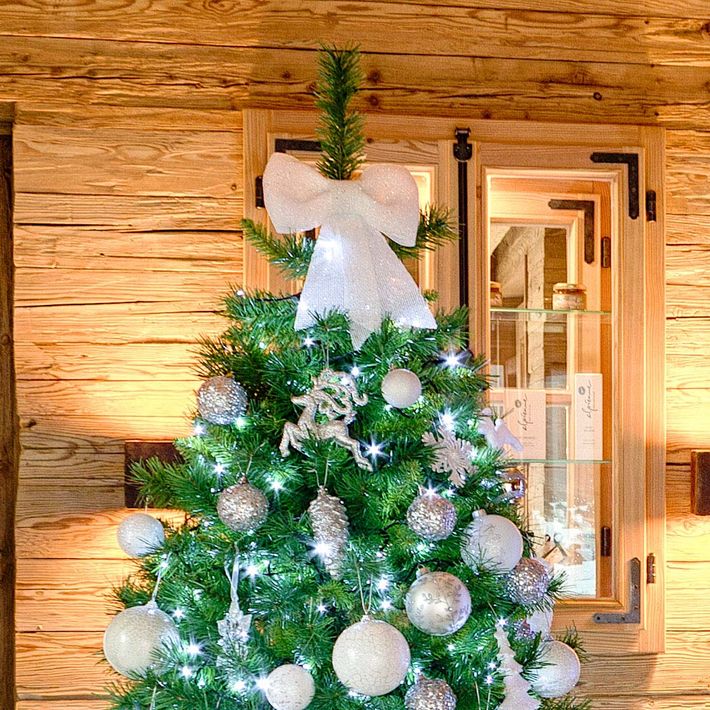 Fiocco bianco usato come puntale di un albero di Natale con decorazioni chiare