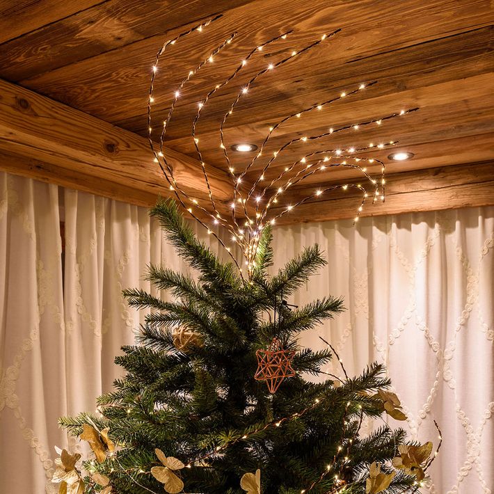 Ramo luminoso a luce calda fissato sulla cima di un albero di Natale